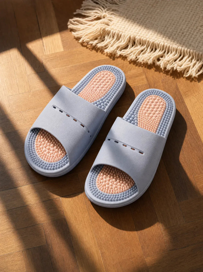 DuskShore — Meridian women's reflexology slides in pale blue, resting on a warm oak floor beside a linen rug in morning light