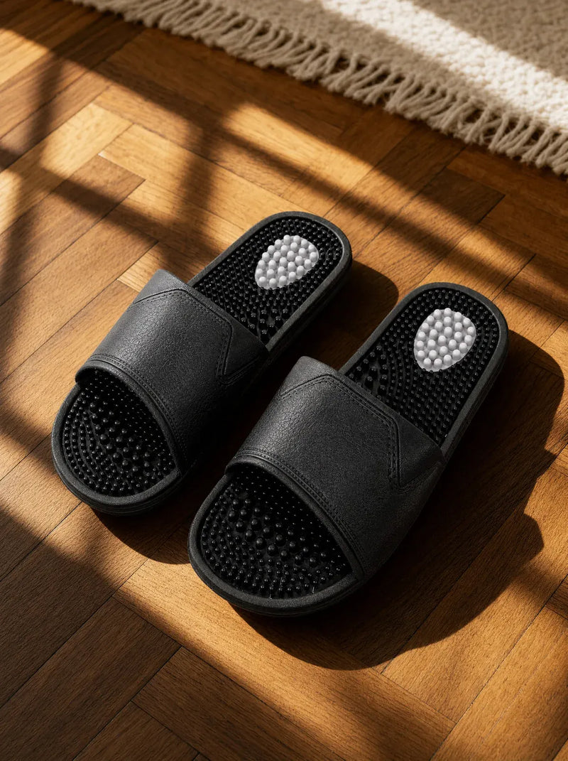 Obsidian — Zenith men's reflexology slides in black, on a warm oak floor beside a linen rug