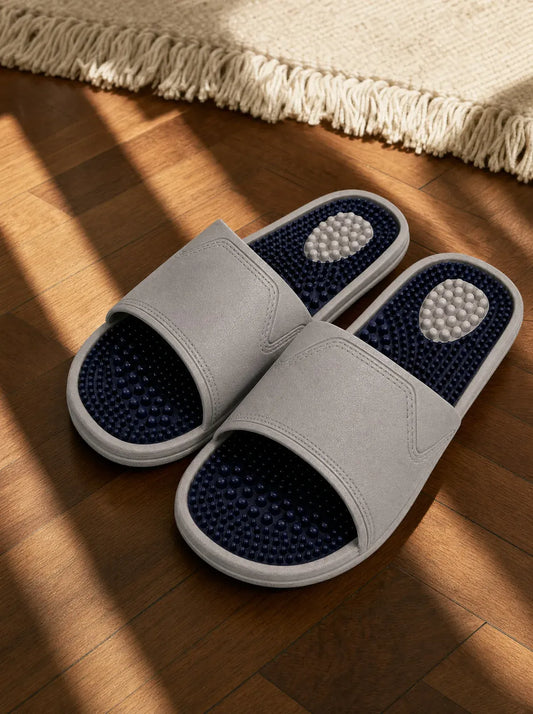 Steelrise — Zenith men's reflexology slides in grey with a navy footbed, on a warm oak floor beside a linen rug