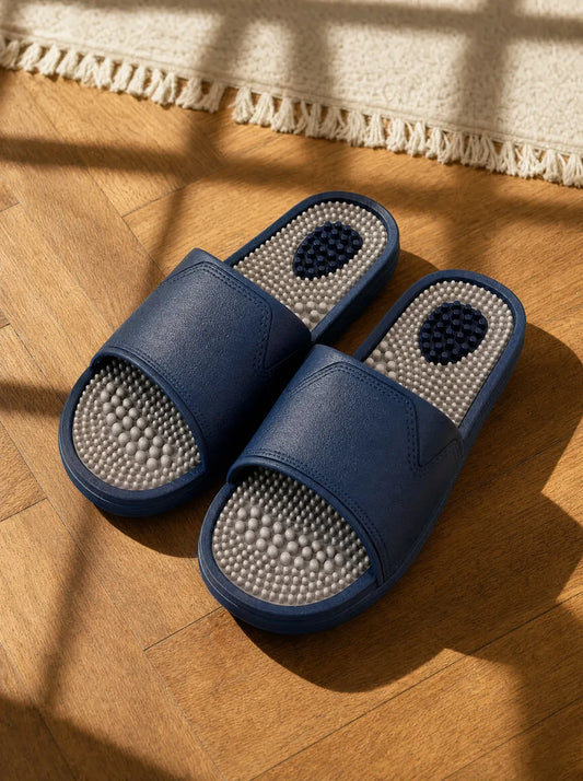 Steelwater — Zenith men's reflexology slides in navy with a pearl grey footbed, on a warm oak floor beside a linen rug